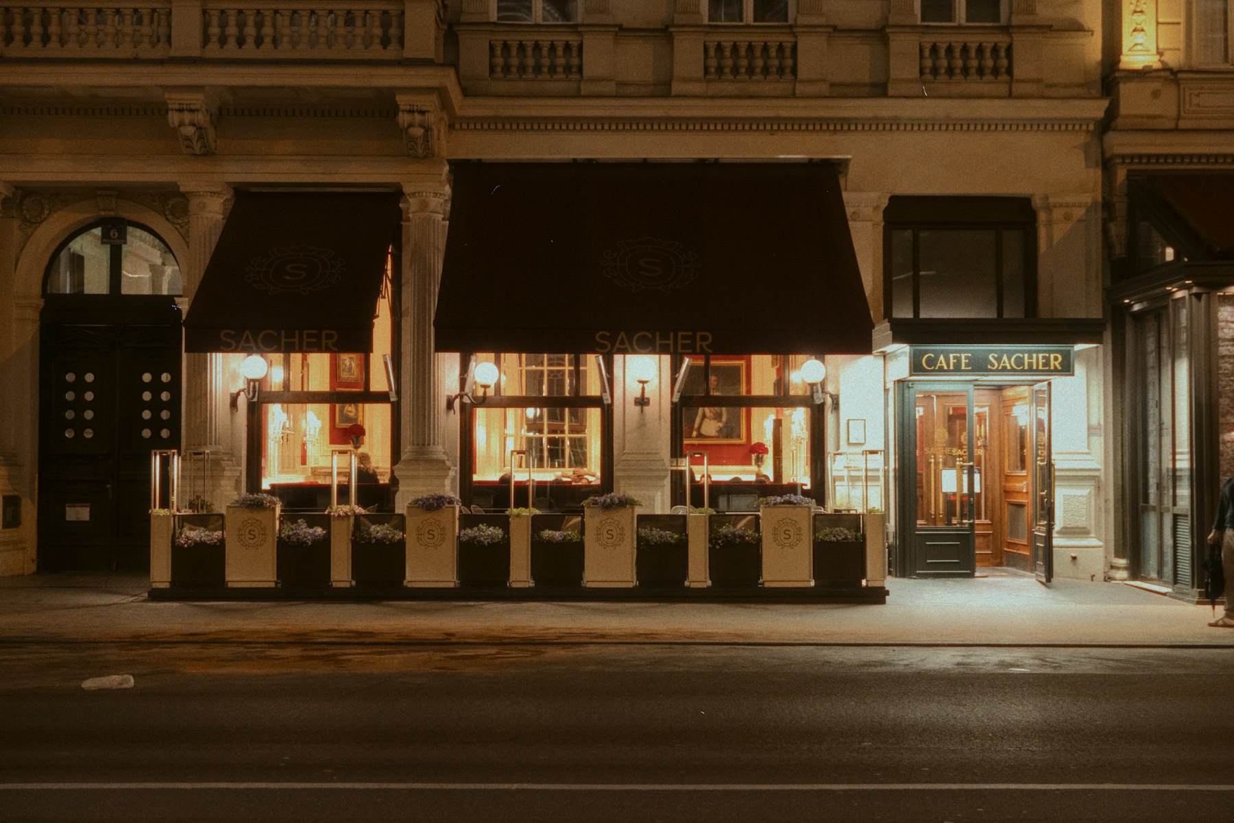 A warmly lit storefront with awnings on a city street